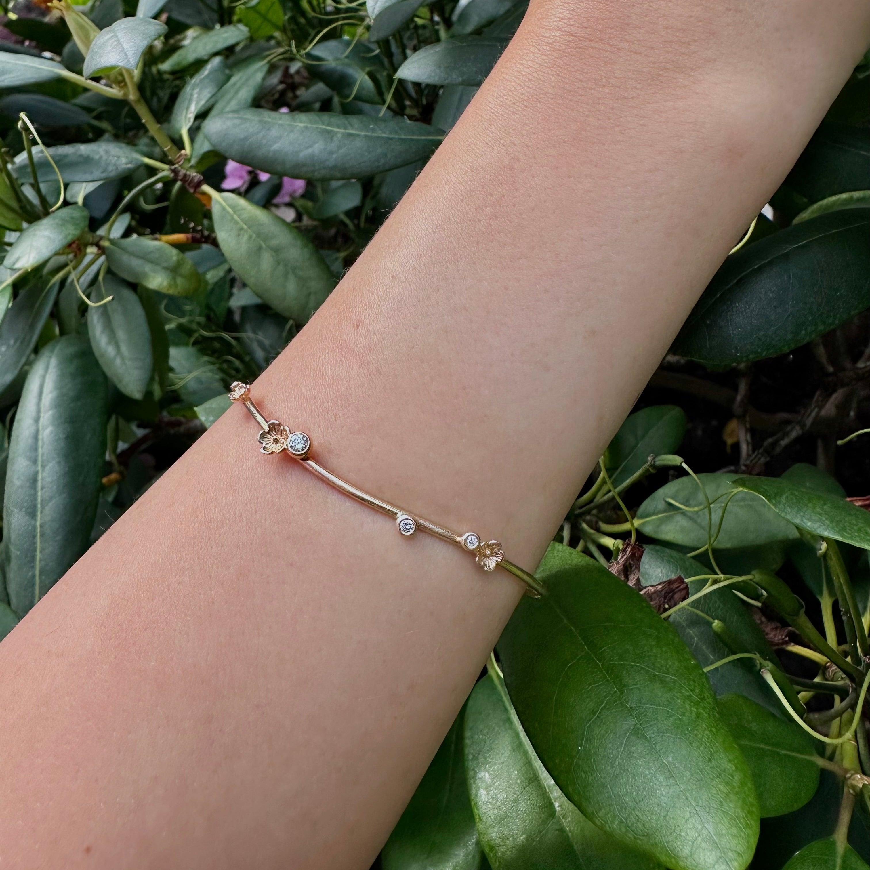 smuk guldarmring med blomster og funklende diamanter vises på arm