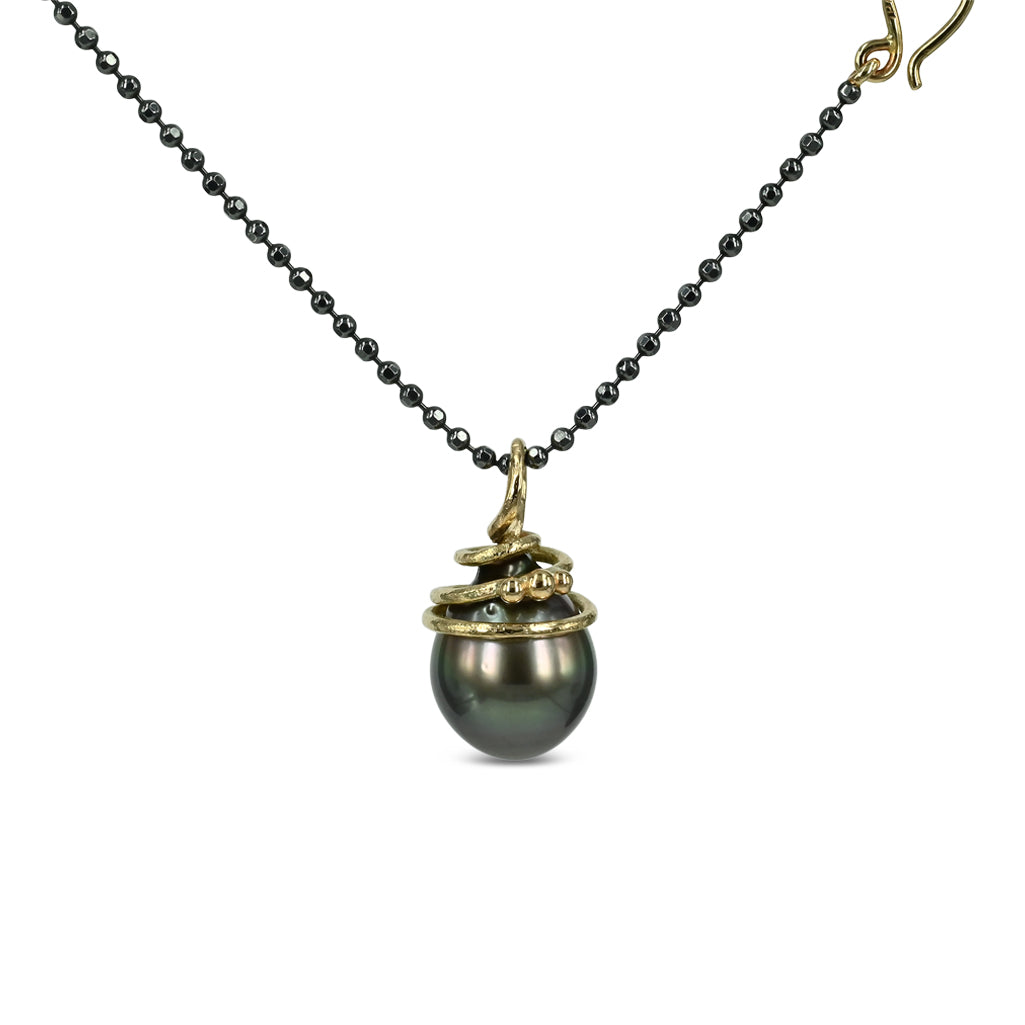 Unik mørk tahiti perle, med 14 kt. guld top, der snor sig elegant omkring perlen.