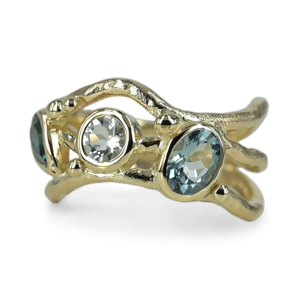 Organisk unika guld ring med lyseblå safir og turmaliner der svinger på ringskinnen. .