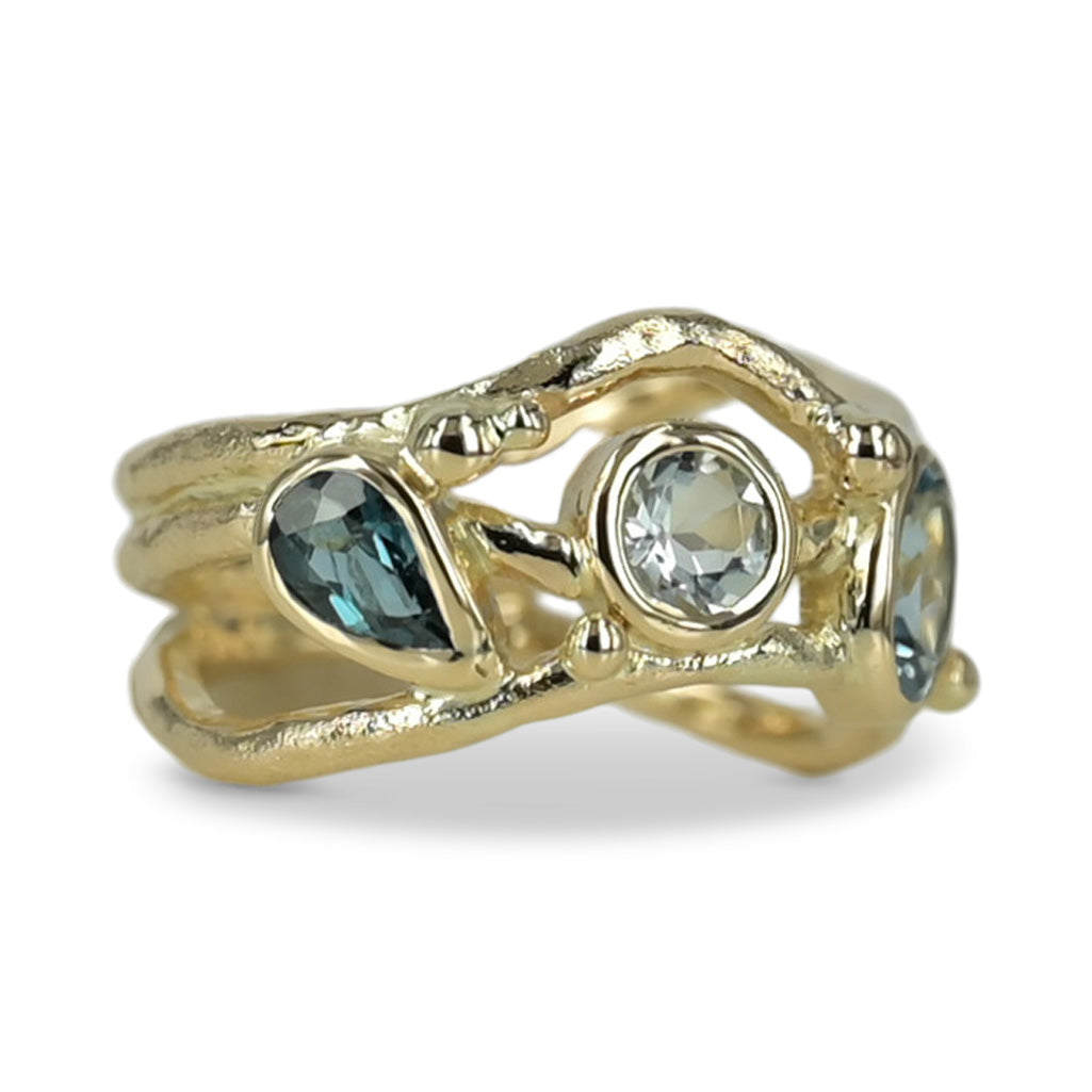 Organisk unika guld ring med lyseblå safir og turmaliner der svinger på ringskinnen. .