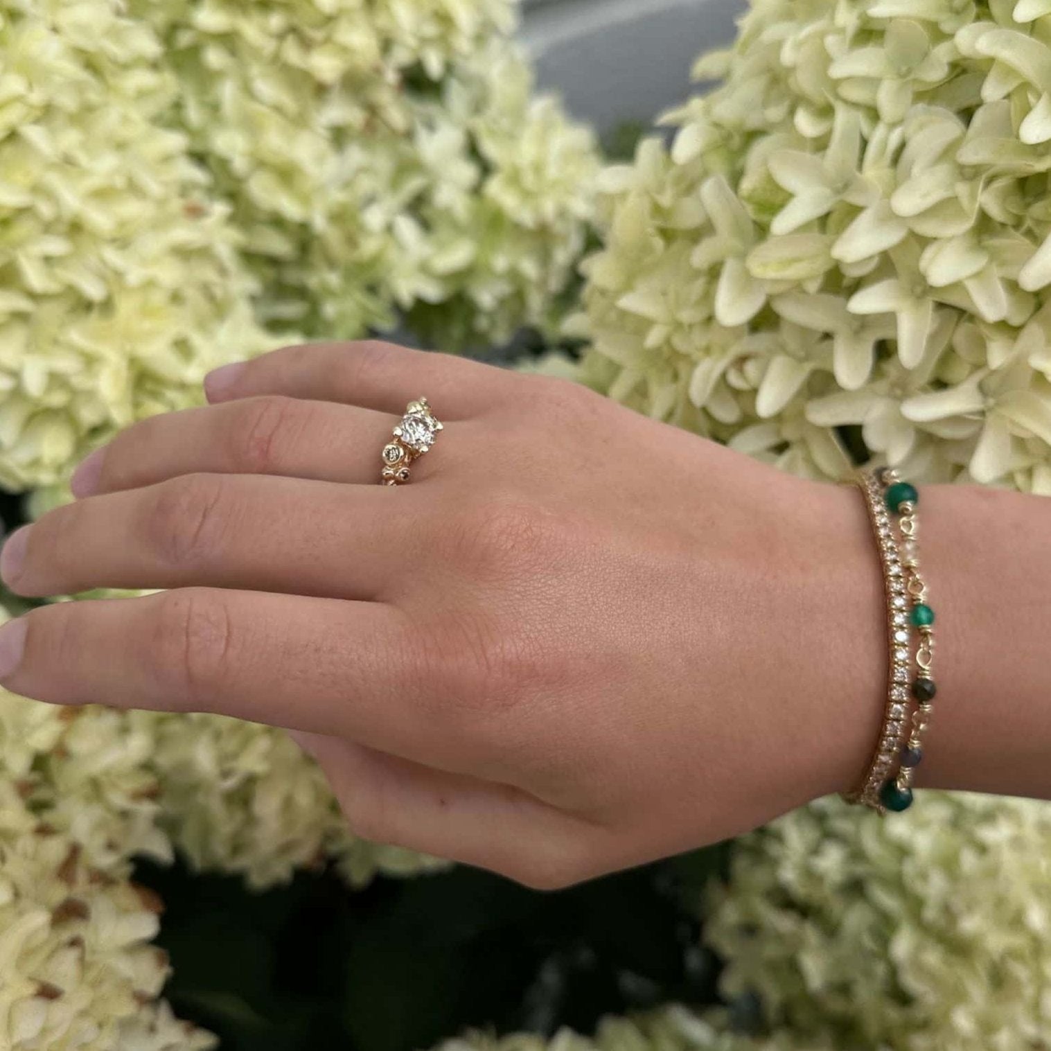 14 karat guldring med champagnefarvet brillanter og diamanter, samt armbånd med grønne ædelsten og guld detaljer.