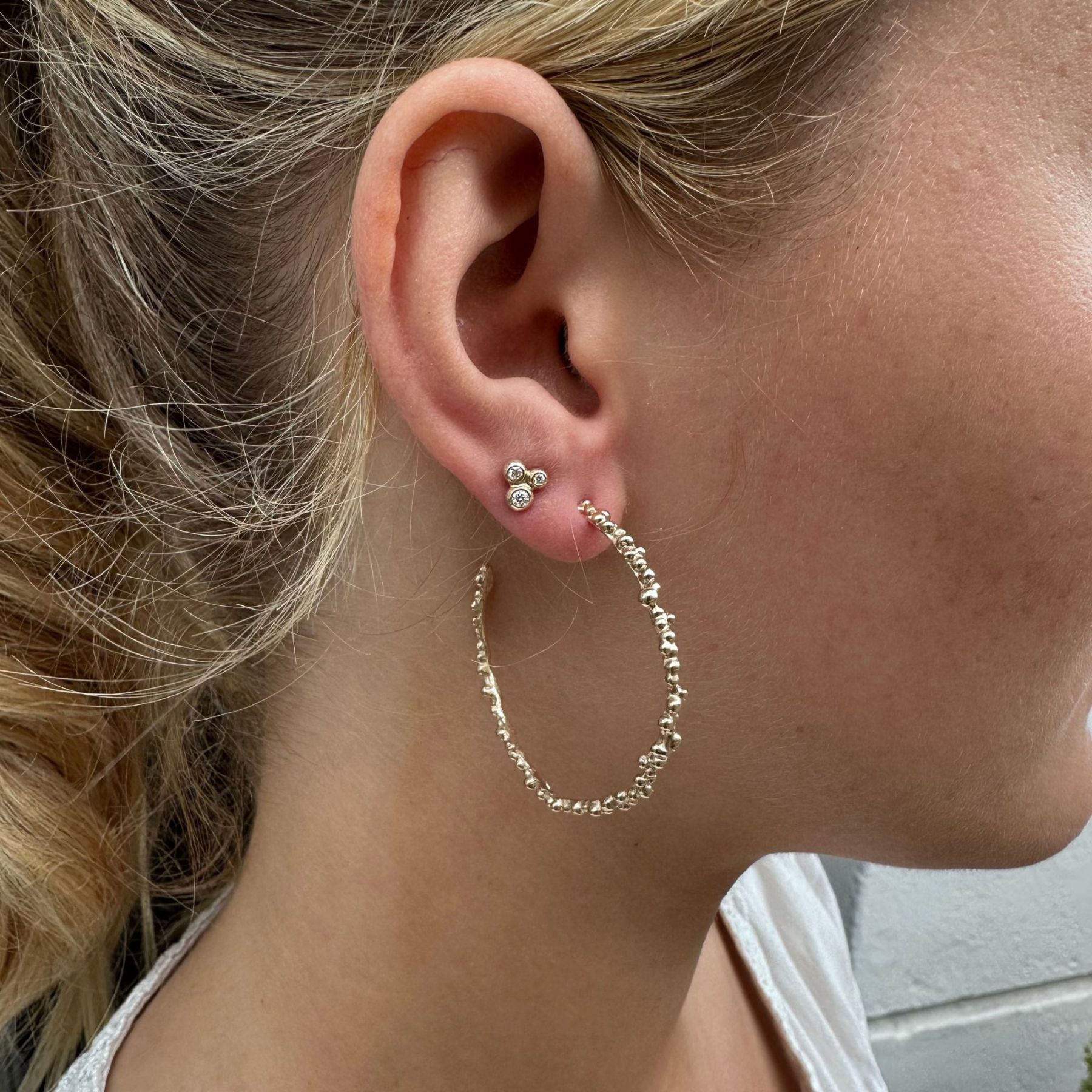 Guld hoops øreringe på kvindes øre med små diamantøreringe