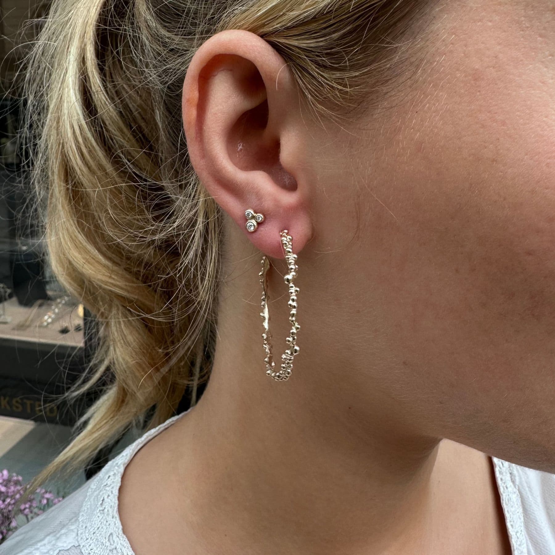 Bubble hoops øreringe i guld bæres af kvinde sammen med en lille diamantørering