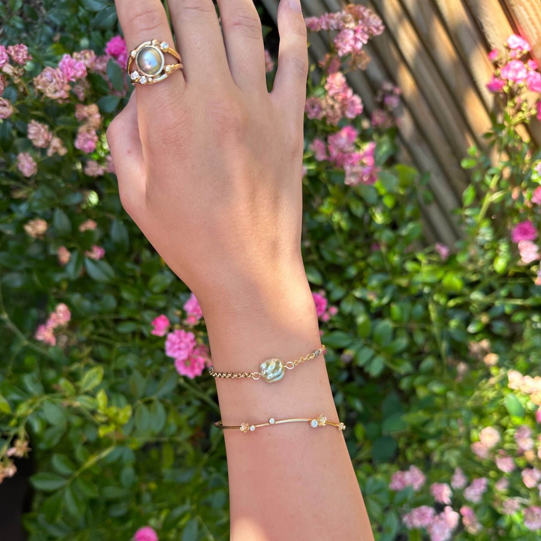 Fairytale 14 karat guldarmbånd med Tahiti keshiperle og dekorativ S-lås, båret sammen med en elegant guldring.