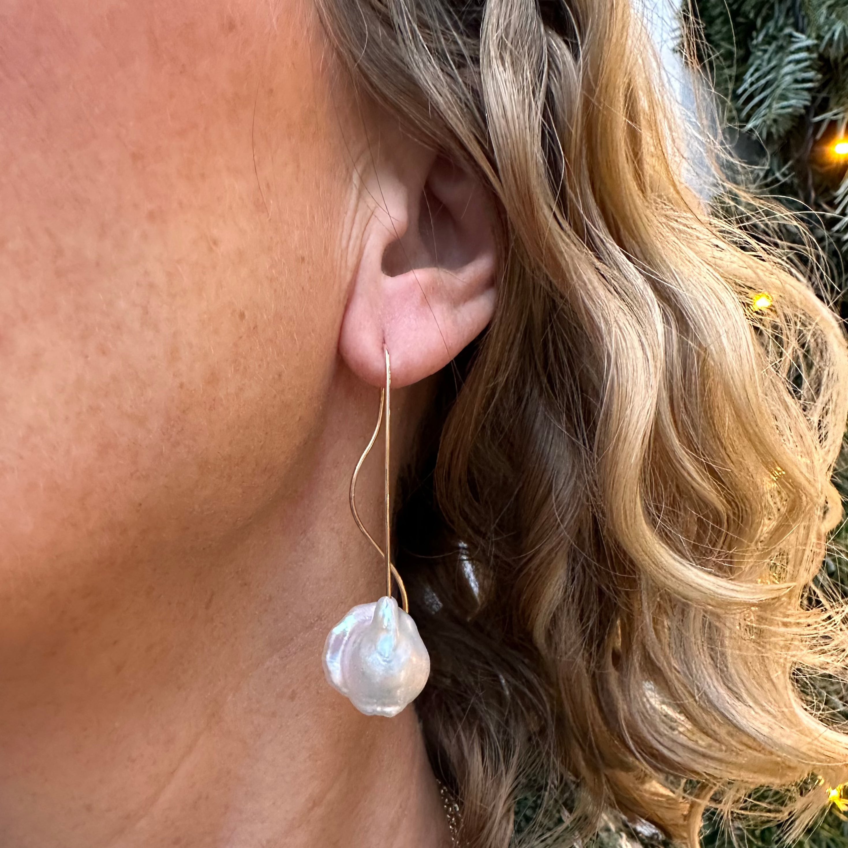 14 kt. øreringe med barok ferskvandsperle Smukke og elegante øreringe, den fine guldbøjle svinger elegant på bagsiden af øret - en fin detalje der gør øreringen let og meget feminin. Perlerne er Hvide med let rosa skær, den barokke overflade gør perlerne mere levende og spændende i øret.