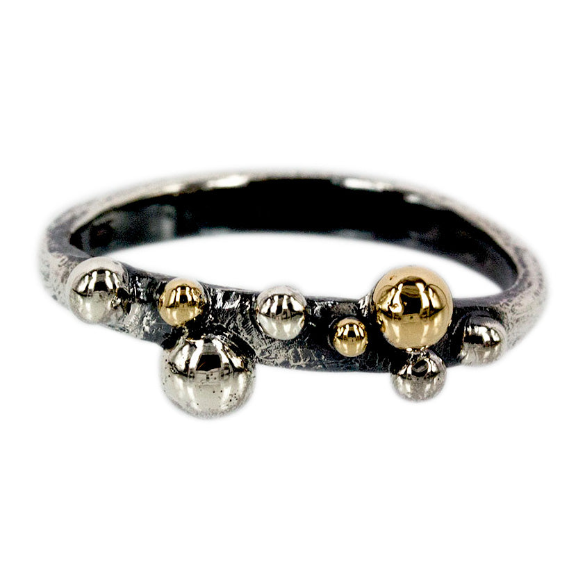 Sølvring med let oxyderet overflade, 14 kt. guld, ringen er skabt med tanke for de små fine bobler der flyder så fint til overfladen i glasset. De små bobler kan sammensættes på utallige måder, og er perfekte sammen med perler,brillanter og vidunderlige ædelsten. Sprudlende bobler der svæver afsted på livets vej, boblerne symbolisere livet små og store øjeblikke.