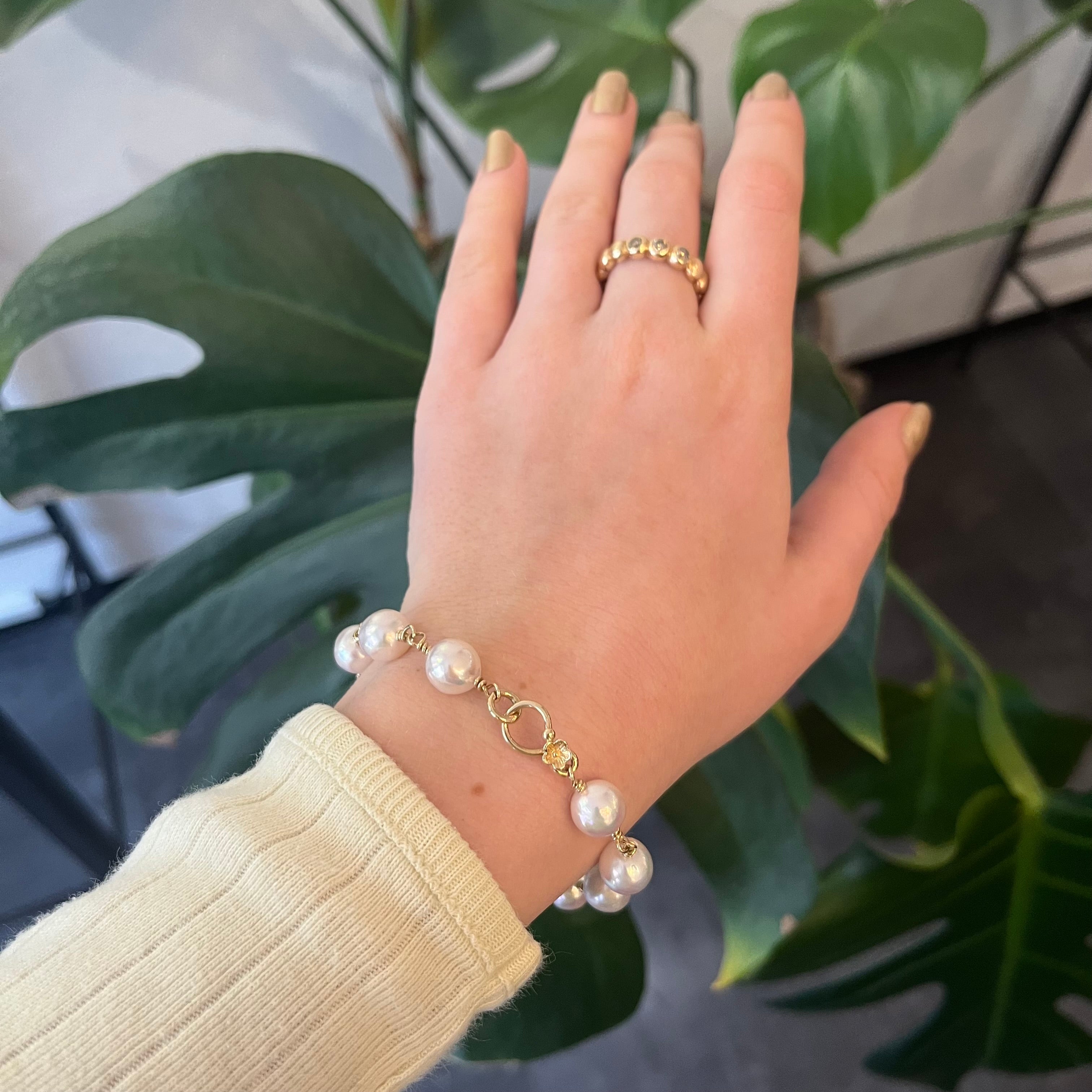 Perlearmbånd med hvide saltvandsperler med guldlås pyntet med blomst - vises på kvindehnd