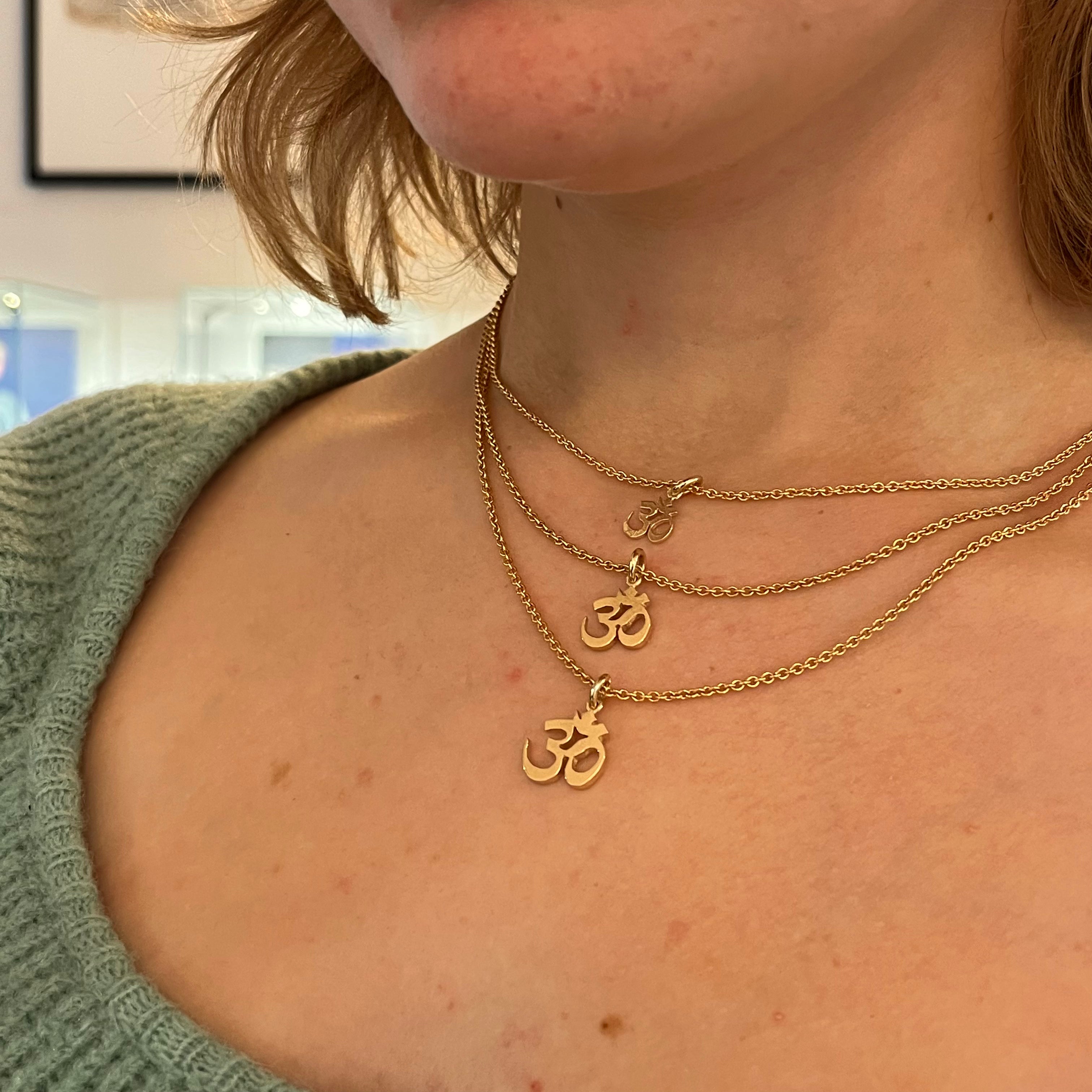 Smukt guldvedhæng med OM symbol. OM symboliserer sandheden om den ultimative virkelighed og kendes fra den åndelige verden. OM er lyden af universet og forbinder en med den guddommelige, den højeste og kilden til al skabelse. Bær dens styrke i dette enkle og tidløse vedhæng.
