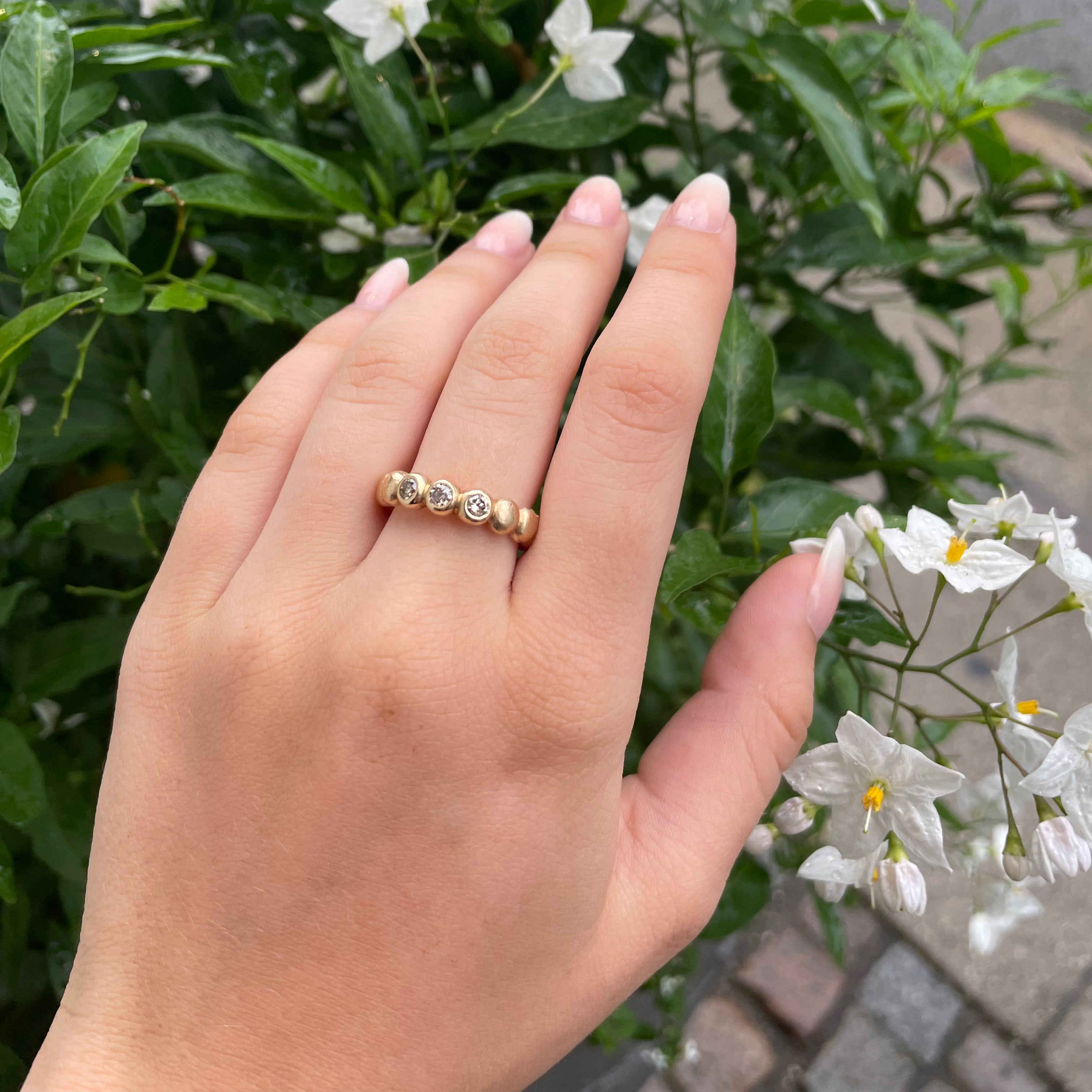 14kt Guldring som består af kugler, der sidder hele vejen rundt om fingeren, i kuglerne kan isættes 0,10ct brillanter efter ønske. Her er isat 3 x 0,10 champagne farvetbrillanter.