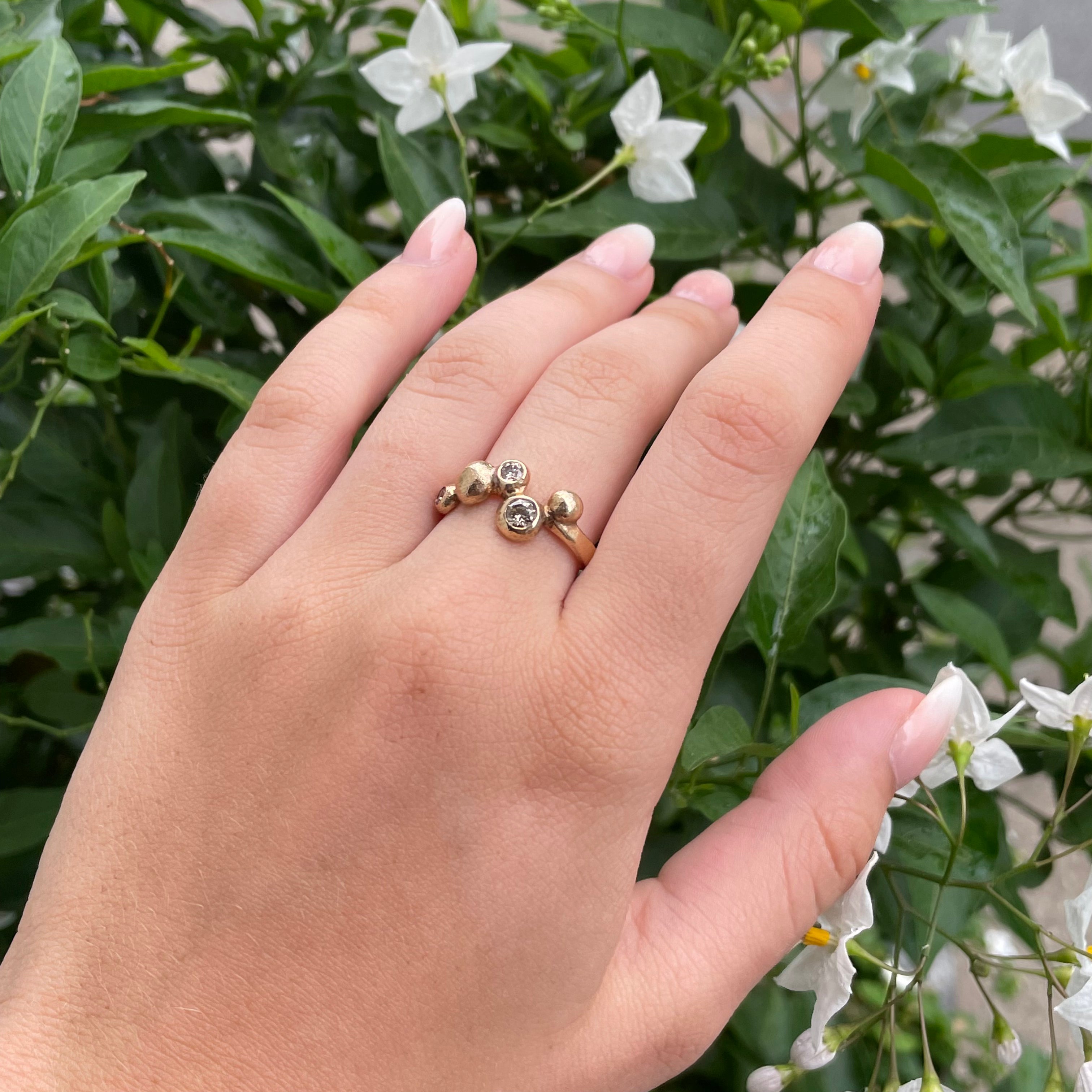 Rå og feminin på en og samme tid, denne ring er skabt med focus på det organiske - ringskinnen danser under din finger i blød bue og ender i smukke nye bobler. Det er isat ass. champagne farvet brillant slebet diamanter i ringen ialt 0.65 ct ialt - der kan efter ønske isættes flere eller andre diamanter i ringen. Diamanter isat : 1 x 0,35 ct , 1 x 0,20 ct samt 1 x 0,10 ct champagnefarvet diamanter i smukt farvespil