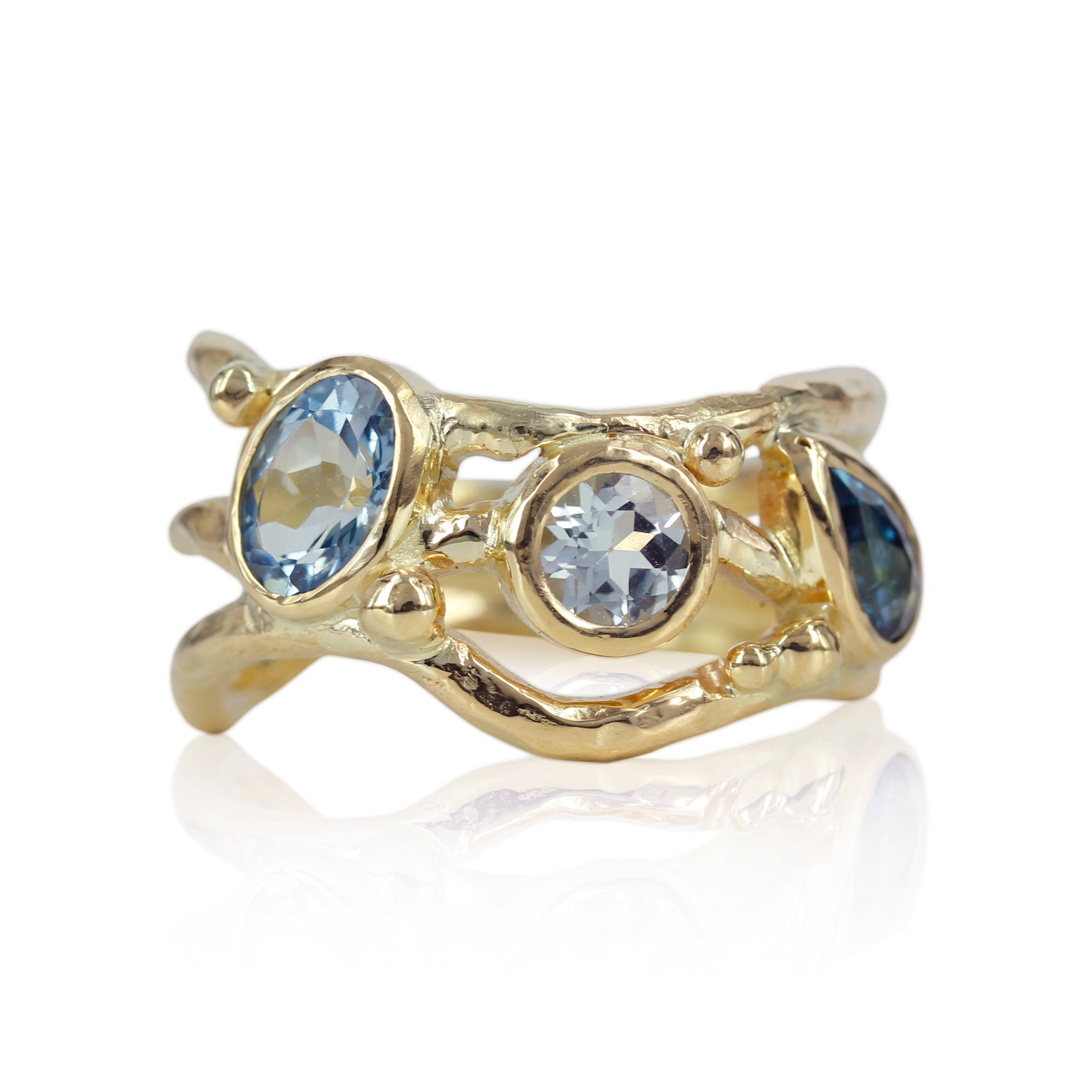 Organisk unika guld ring med lyseblå safir og turmaliner der svinger på ringskinnen. 
